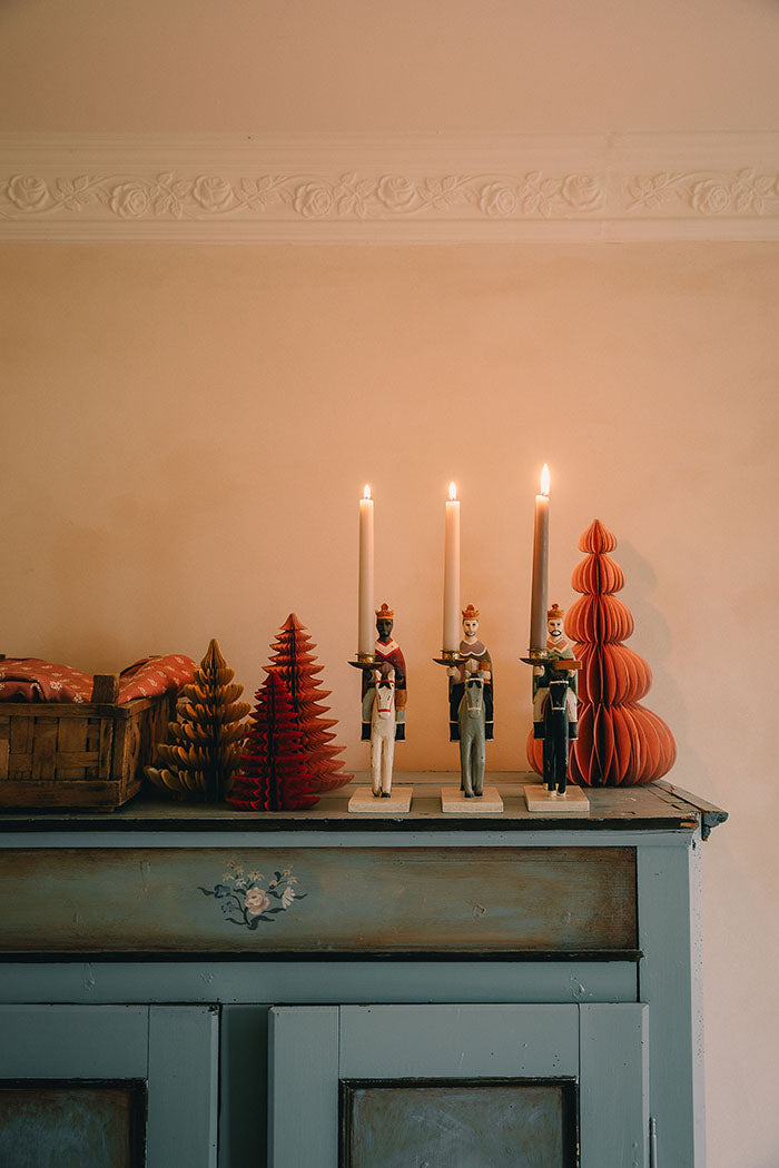 Decorative setup with candles, trees, and wise men figurines with candles on a mantelpiece.