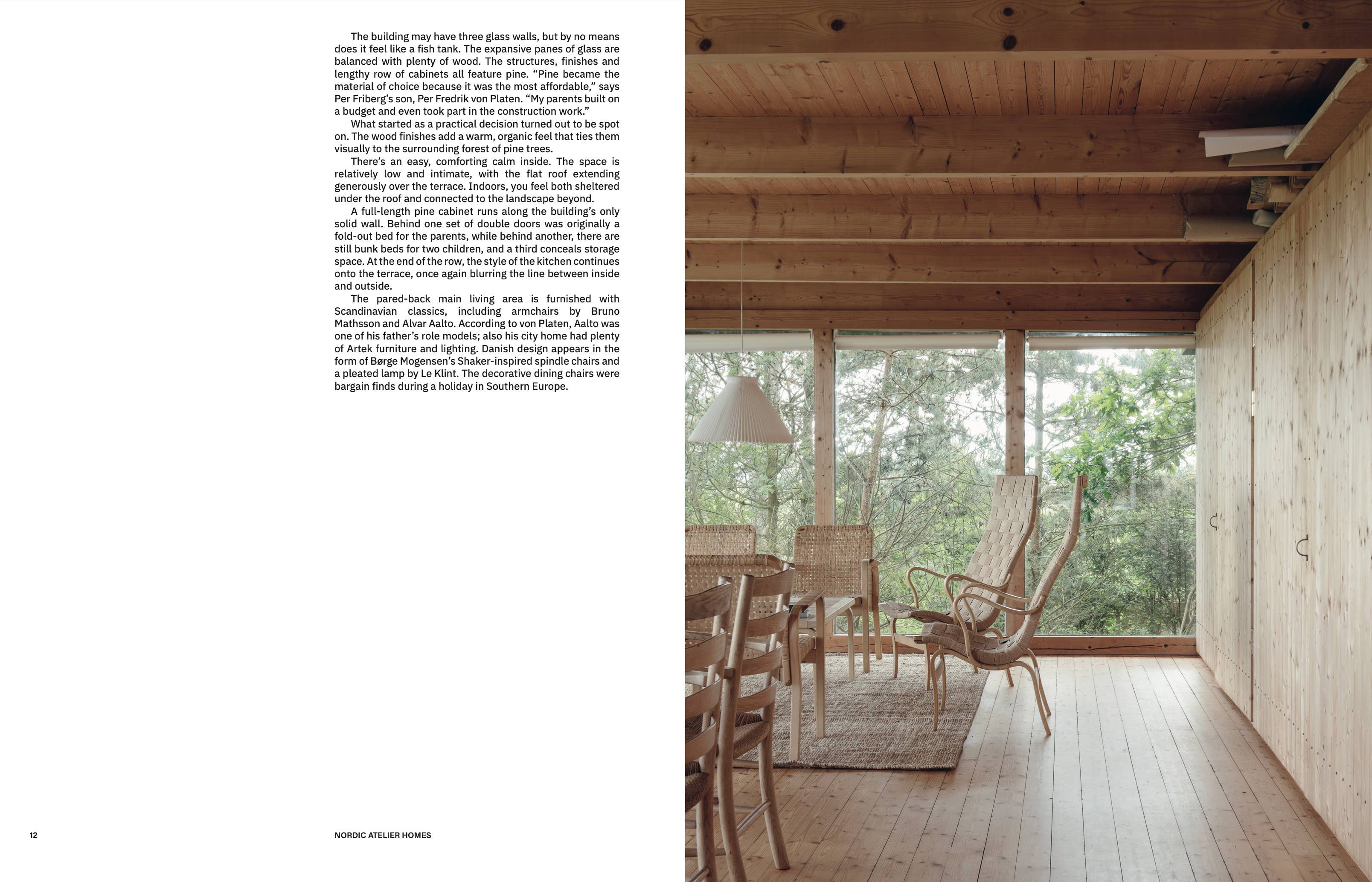 Dining area with wooden furniture and large windows overlooking a forest.