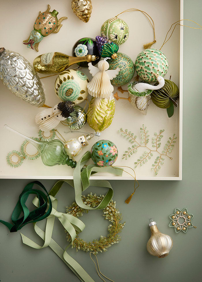 Collection of decorative ornaments on a white shelf with a green background