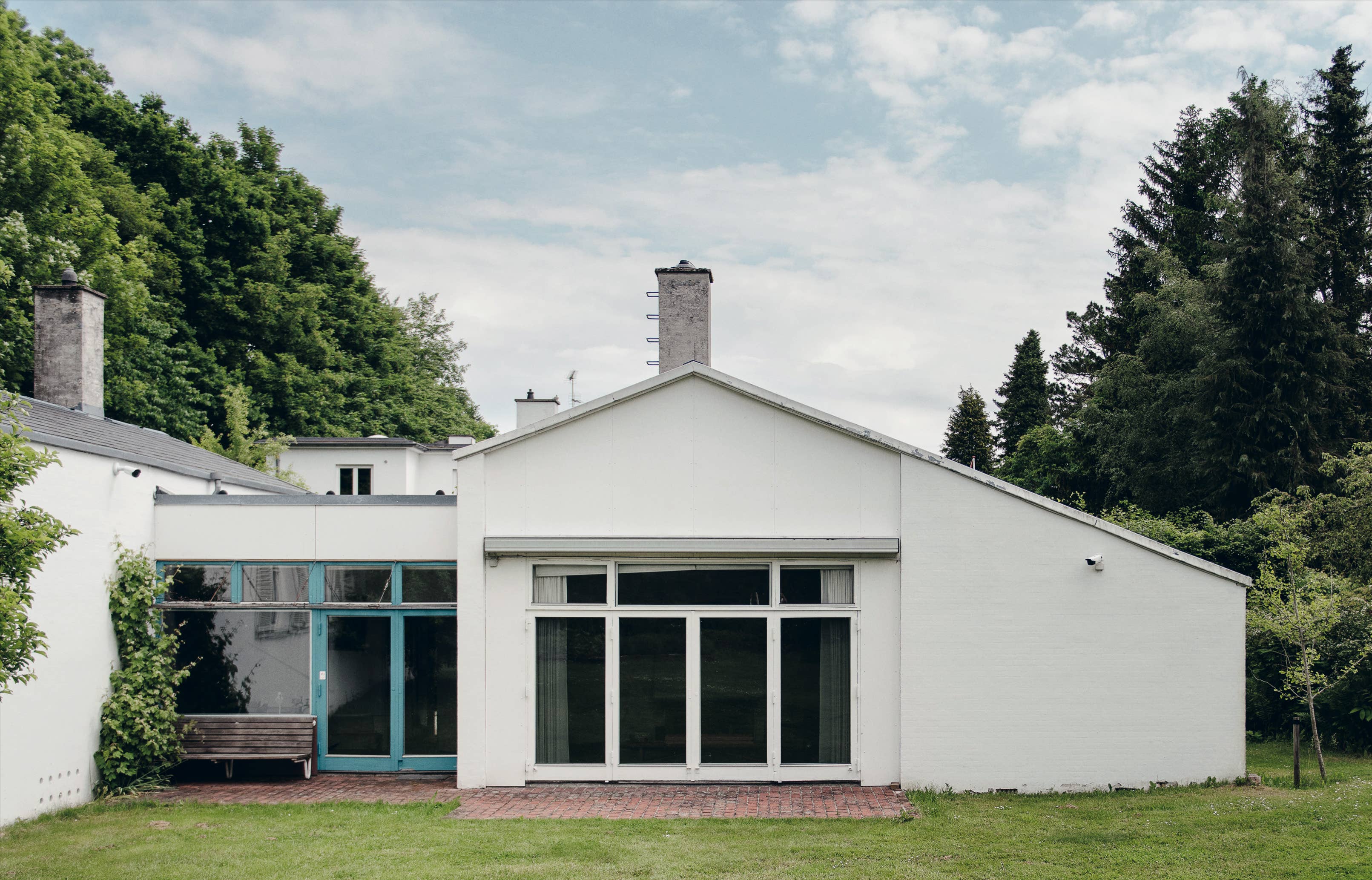 Modern white house with large windows surrounded by trees