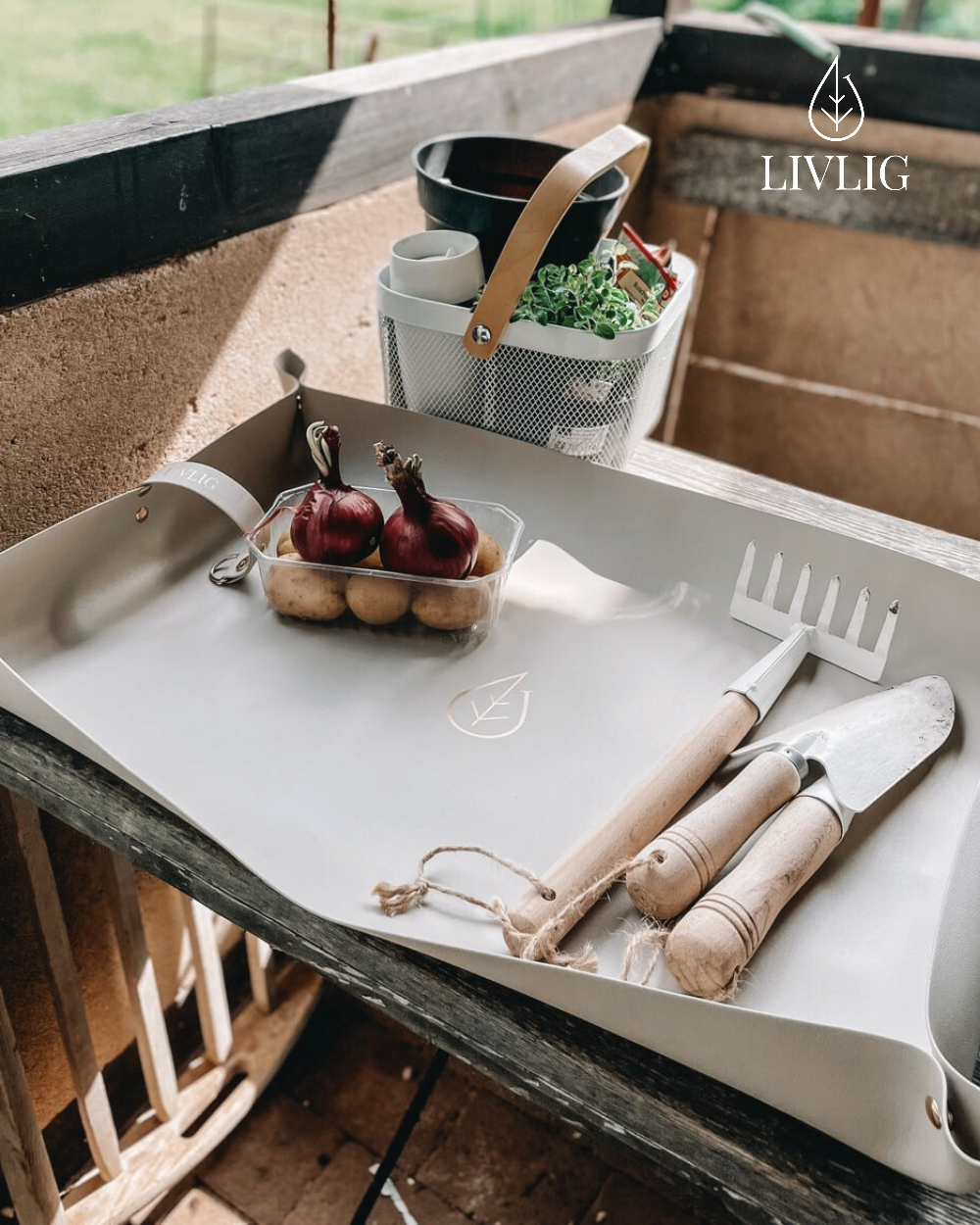 White tray with gardening tools and produce on a wooden surface, featuring the LIVLIG brand.