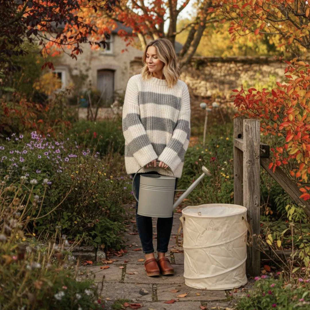 Woman in a striped sweater standing in a garden with autumn foliage