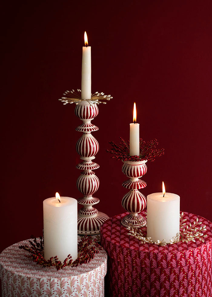 Decorative candles on ornate candlesticks against a dark red background