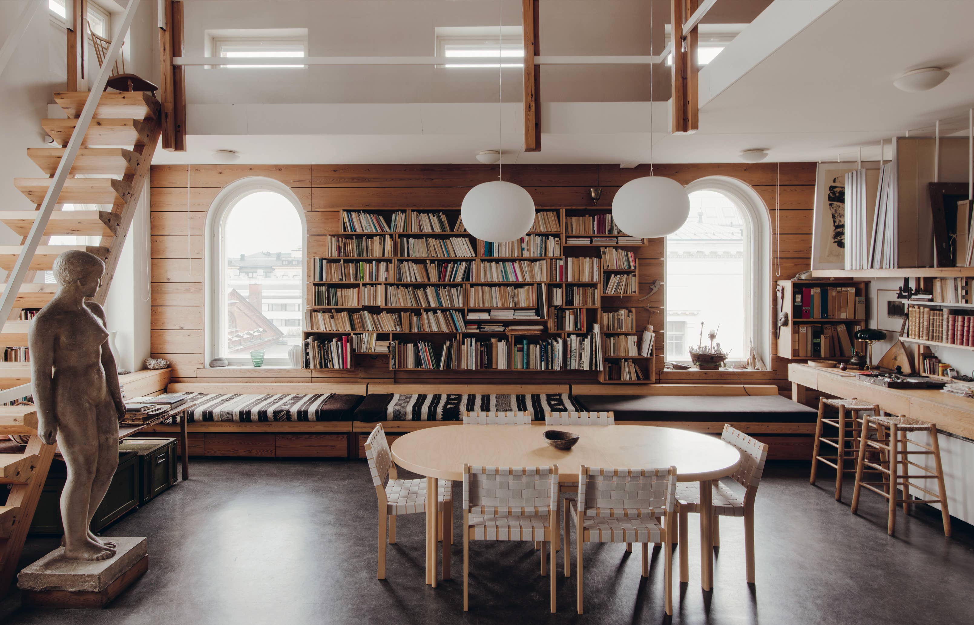 Modern interior with bookshelves, dining table, and staircase.